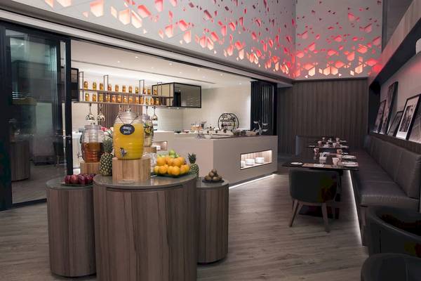 Frühstücksbereich im Mysk Al Mouj Hotel mit Obst, Säften und Sitzgelegenheiten.