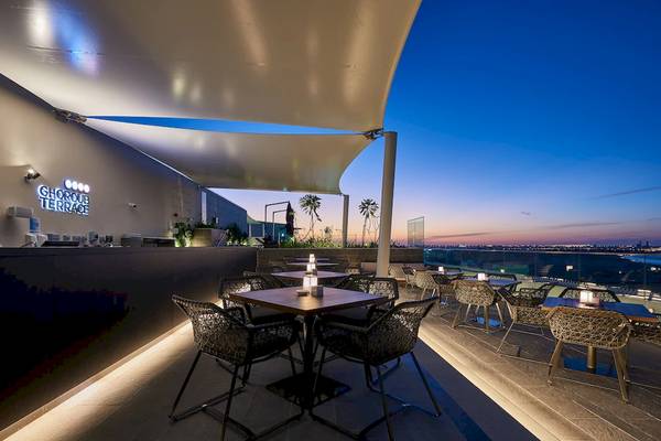 Außenbereich der Ghoroub Terrace im Mysk Al Mouj Hotel mit abendlichem Blick auf die Stadt.
