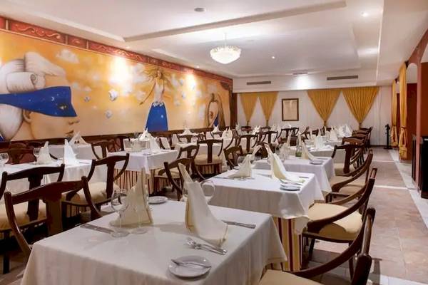 Innenbereich eines Restaurants im Viva Azteca by Wyndham Hotel mit gedeckten Tischen und einer großen Wandmalerei.