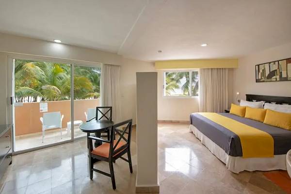 Hotelzimmer von Viva Azteca by Wyndham mit einem Bett, einem Tisch und Stühlen und einem Balkon mit Aussicht auf Bäume.