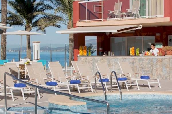 Poolbereich des Universal Hotel Neptuno mit Bar und Liegestühlen am Meer.