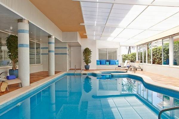 Innenpool im Universal Hotel Neptuno mit Loungebereich und Pflanzen.