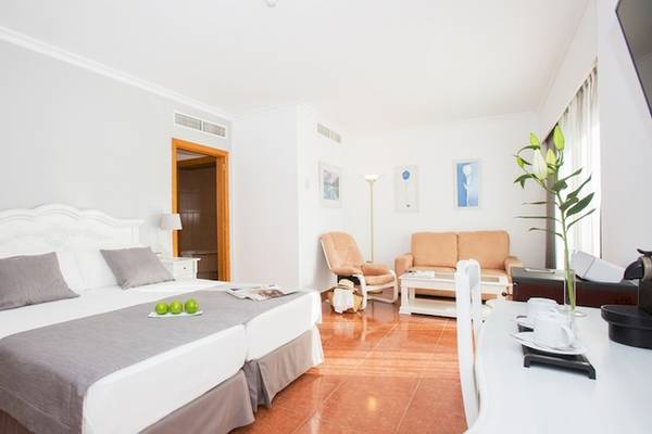 Doppelzimmer im Universal Hotel Neptuno mit zwei Betten, einem Wohnzimmerbereich, einem Couch, einem Tisch und einem Blumentopf.