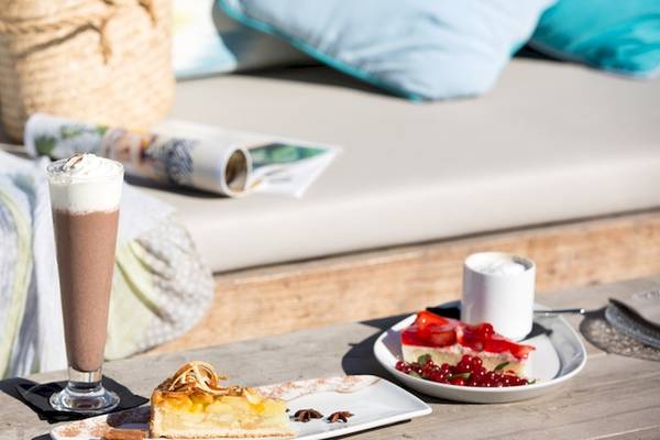 Frühstückstisch im Universal Hotel Neptuno mit Kuchen und Getränken auf einer Terrasse.