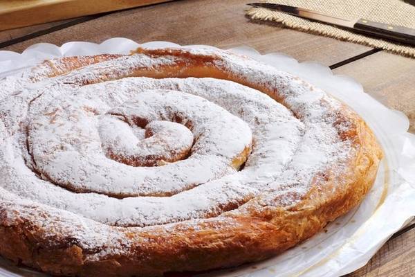 Ein Spiralgeburtstagskuchen mit Puderzucker bestreut auf einem weißen Teller.