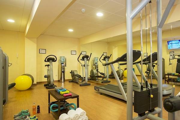 Fitnesscenter im Universal Hotel Neptuno mit Laufbändern, Hanteln und Trainingsgeräten.