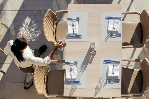 Ein Kellner bereitet einen Tisch im Freien im Universal Hotel Neptuno vor.