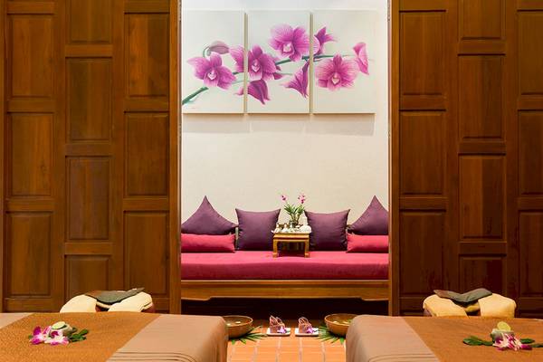 Spa-Behandlungsraum im Dewa Phuket Resort & Villas mit weichen Kissen und Orchideen.