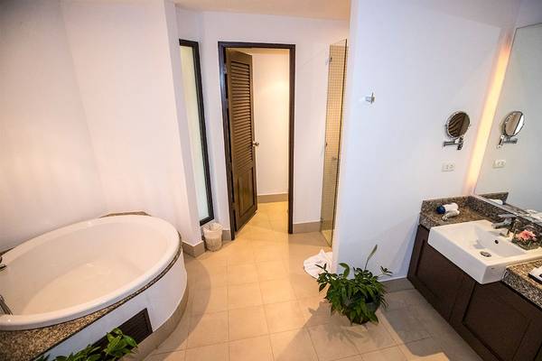 Badezimmer im Dewa Phuket Resort & Villas mit Badewanne, Spiegel und Waschbecken.