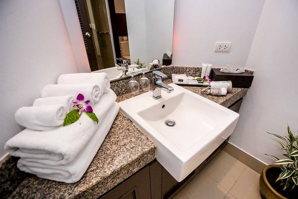 Badezimmer im Dewa Phuket Resort & Villas mit weißem Waschbecken, Handtüchern und Blumendekor.