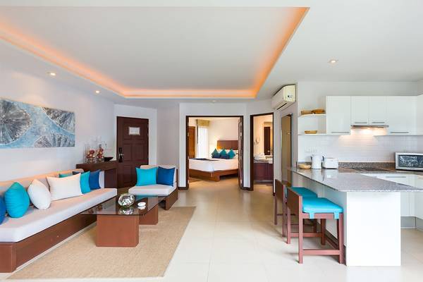 Innenansicht des Wohnbereichs im Dewa Phuket Resort & Villas mit Sofa, Tisch und Küche.