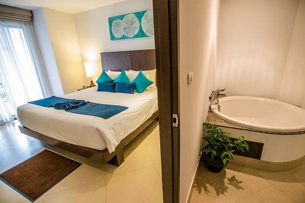 Schlafzimmer im Dewa Phuket Resort & Villas mit einem Bett, Kissen, Badewanne und Pflanze.