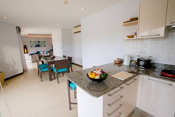 Innenansicht der Küche im Dewa Phuket Resort & Villas mit Esstisch und Obstschale.