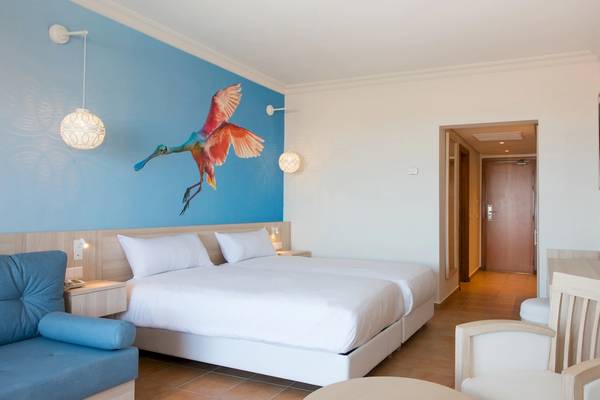 Doppelzimmer im Iberostar Founty Beach Hotel mit zwei Betten, blauer Wand und Vogelmalerei.