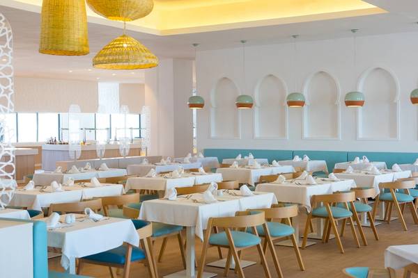 Innenansicht des Restaurants im Iberostar Founty Beach Hotel mit weißen Tischen, blauen Sitzen und gelben Deckenleuchten.