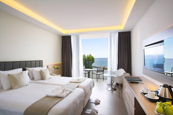 Doppelzimmer mit Meerblick im Royal Apollonia Beach Hotel, zwei Betten, Schreibtisch und Balkon.