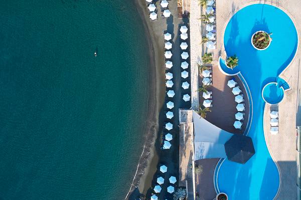 Oberflächenansicht des Royal Apollonia Strandhotels mit Pool und weißen Sonnenschirmen.