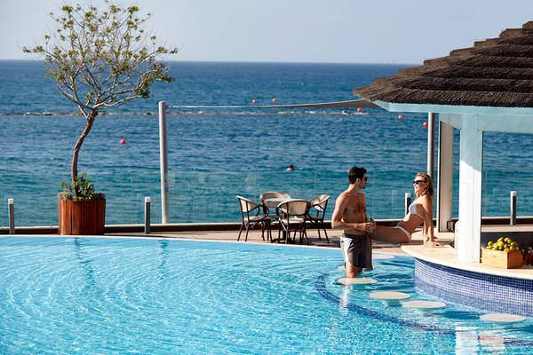 Paar am Pool im Royal Apollonia Beach Hotel mit Blick auf das Meer