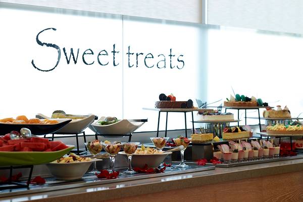 Buffet mit süßen Häppchen im Royal Apollonia Beach Hotel, darunter Kuchen, Obst und Desserts.