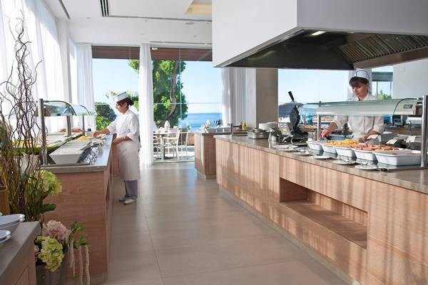 Mitarbeiter im Restaurant des Royal Apollonia Beach Hotels, das Essen serviert und auf einem Tisch an der Küste steht.