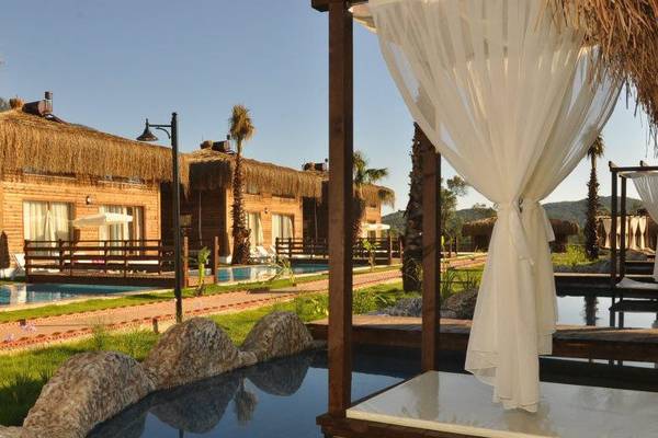 Außenbereich des Sahra Su Holiday Village & Spa mit hübsch dekorierten Holzhütten und einem Pool.