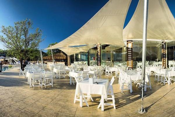 Outdoor-Restaurant im Sahra Su Holiday Village & Spa mit weißen Tischen und Stühlen unter weißen Segeln.