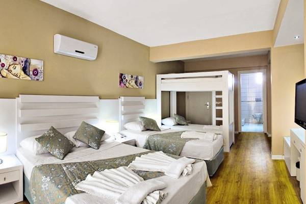 Hotelzimmer von Sahra Su Holiday Village & Spa mit zwei Betten, Klimaanlage und Kunstwerken an der Wand.