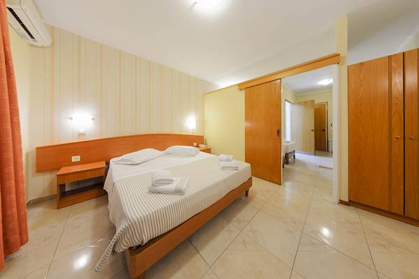 Schlafzimmer im Zante Palace Hotel mit Doppelbett, Nachttischen und Kleiderschränken.