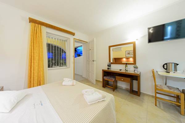 Innenansicht eines Zimmers im Zante Palace Hotel mit einem Bett, Fenster und Schreibtisch.