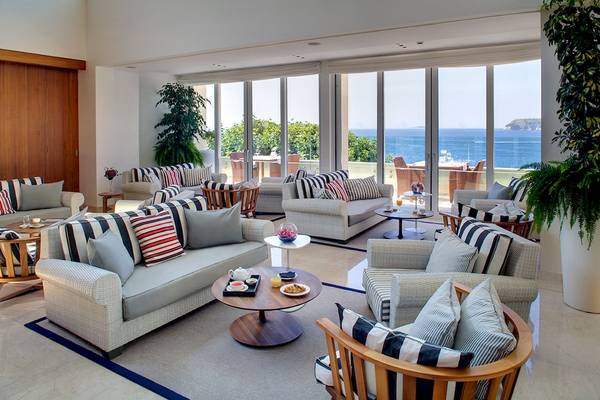 Hotellobby mit vielen Sofas und Sesseln, große Fenster mit Meerblick