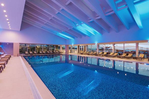 Innenpool des Hotels Dubrovnik President Valamar Collection mit Loungestühlen und blauer Beleuchtung.