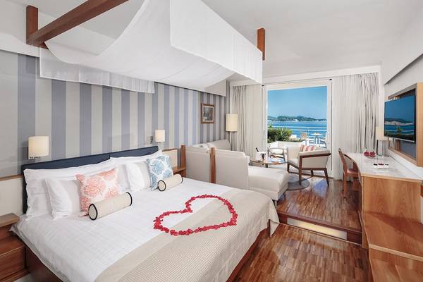 Hotelzimmer im Dubrovnik President Valamar Collection mit Herz aus Rosenblättern auf dem Bett und Blick auf das Meer.