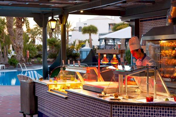 Ein Koch im Seaside Los Jameos Hotel serviert an einem Poolbar-Tresen.