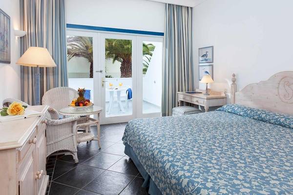 Innenansicht eines Schlafzimmers im Seaside Los Jameos Hotel mit Bett, Balkon, Tisch und Stühle.