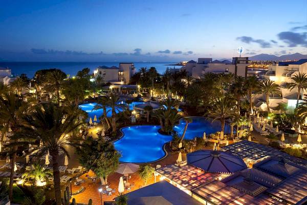 Abendliche Aussicht auf das Seaside Los Jameos Hotel mit Swimmingpool und angelegter Landschaft.