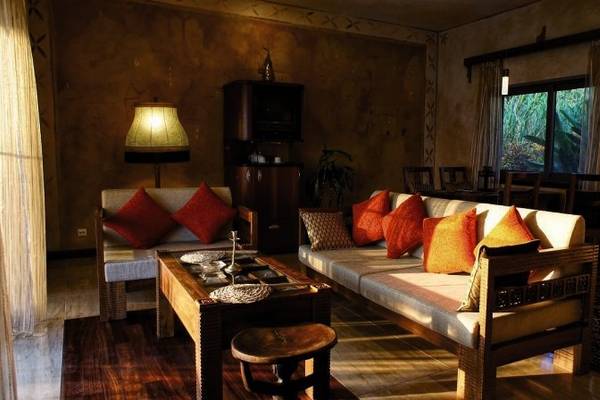 Wohnzimmer im Zanzi Resort mit Sofas, Tisch, Lampen und einem Blick auf den Garten.