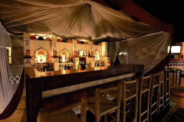 Innenansicht der Bar im Zanzi Resort mit einer thematischen Einrichtung und gefüllten Regalen.