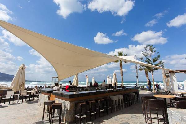 Außenbar im Olympos Beach Resort mit Gästestühlen und Sonnenschirmen am Strand