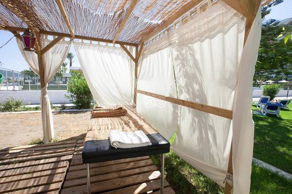 Massagebereich im Garten des Olympos Beach Resort mit weißen Vorhängen und Liege.