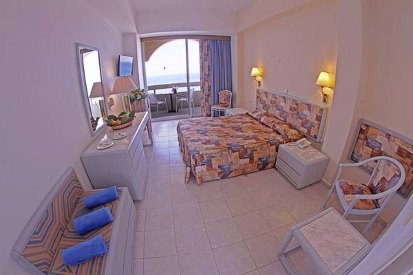 Innenansicht eines Hotelzimmers im Olympos Beach Resort mit einem Bett, Balkonzugang und Meerblick.