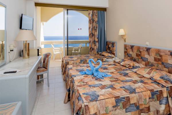 Doppelzimmer im Olympos Beach Resort mit Meerblick und zwei Betten, einem Schreibtisch und einem Balkon.