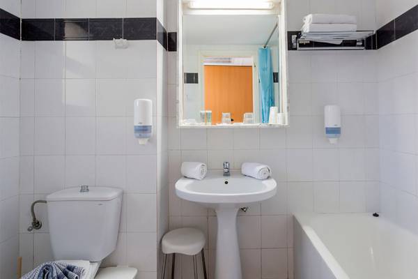 Badezimmer im Olympos Beach Resort mit Badewanne, Toilette, Waschbecken und Spiegel.