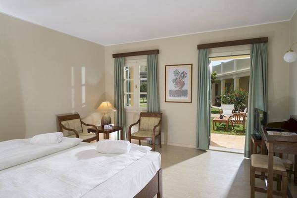 Doppelbettzimmer im Kalimera Kriti Hotel & Village Resort mit offener Tür und Gartenblick.