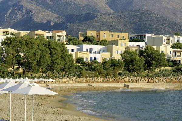 Kalimera Kritis Hotel & Village Resort mit Blick auf die Strand, weiße Sonnenschirme und blaue Liegen