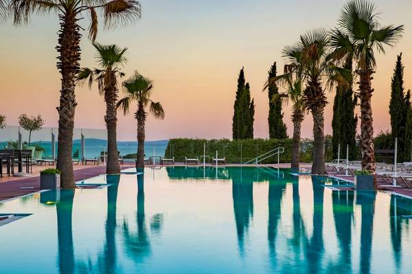 Außenpool des Radisson Blu Resort Split bei Sonnenuntergang mit kristallklarem Wasser und Palmen