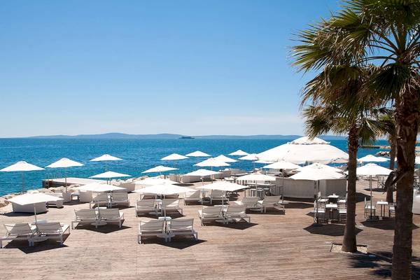 Terrasse des Radisson Blu Resorts Split mit weißen Sonnenschirmen und Stühlen am Meer