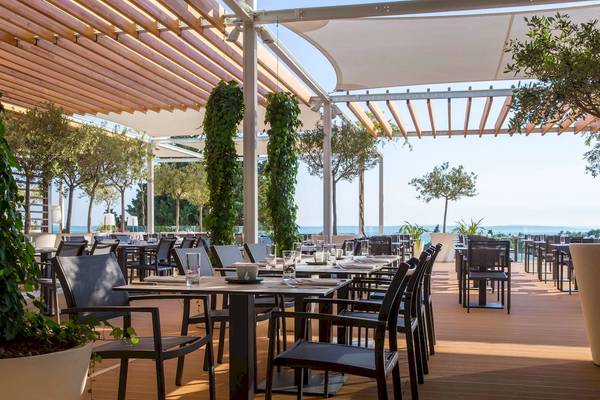 Außenterrasse des Radisson Blu Resort Split mit Tischen und Stühlen, überdacht von Holzbalken.