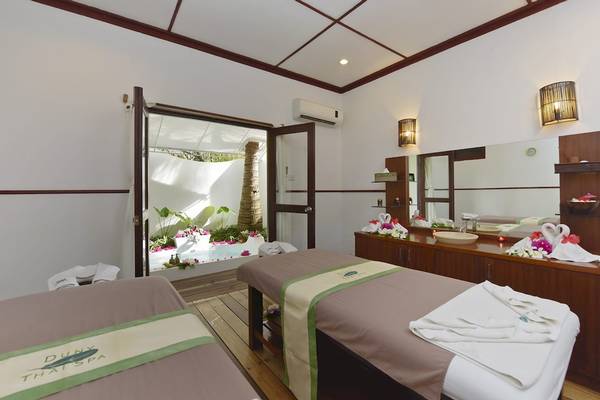 Thai Spa Behandlungsraum im Angaga Island Resort & Spa mit zwei Massagebetten, einem Whirlpool und einem großen Spiegel.