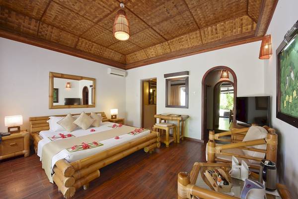 Schlafzimmer im Angaga Island Resort & Spa mit einem großen Bett, Kissen, Lampen und einem Fernseher.