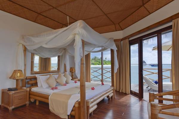 Ein Bett im Angaga Island Resort & Spa mit Blick auf das Meer von einer Terrasse aus.